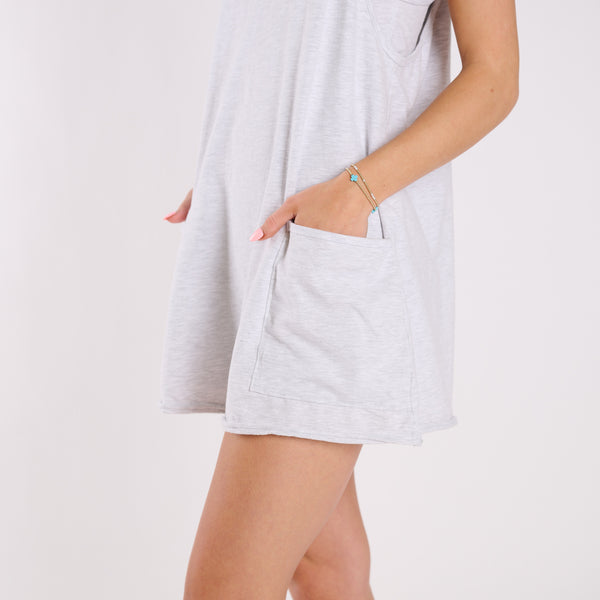 Woman wearing a heather white sleeveless dress on a plain background