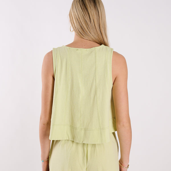  Person wearing a light green sleeveless top and pants on a white background