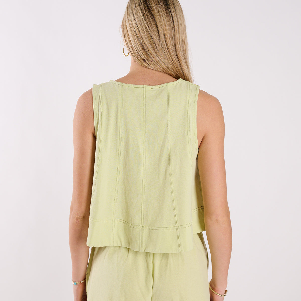 Person wearing a light green sleeveless top and pants on a white background