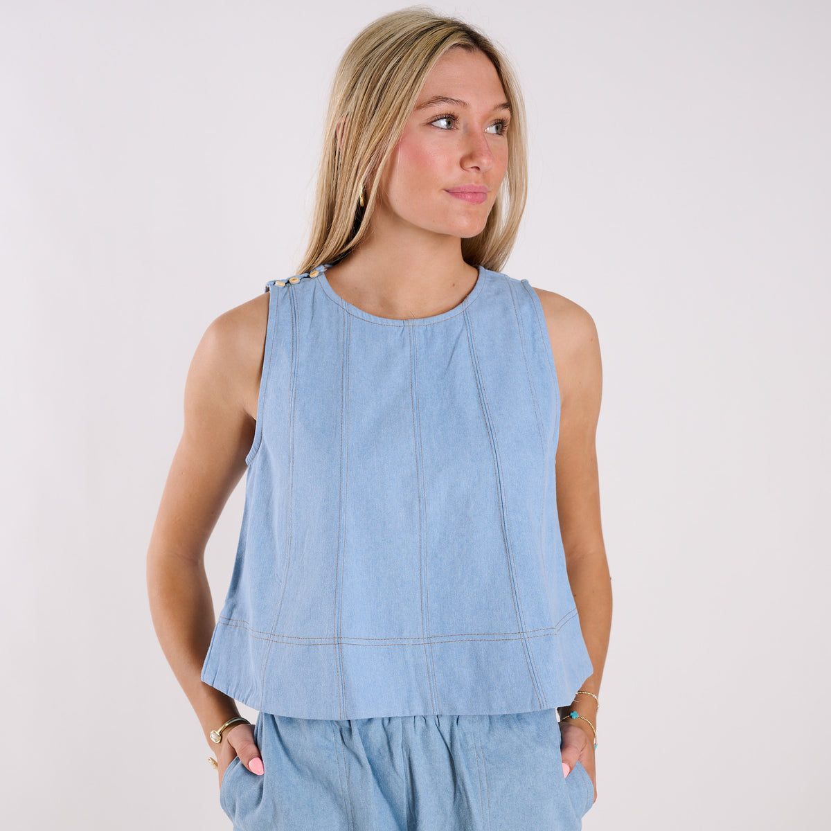 Woman wearing a light blue sleeveless top against a white background
