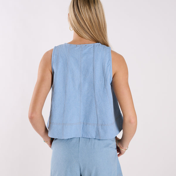  Woman wearing a light blue sleeveless top and pants on a white background