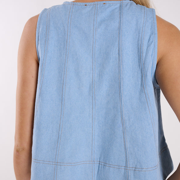  Light blue denim sleeveless top on a person against a white background