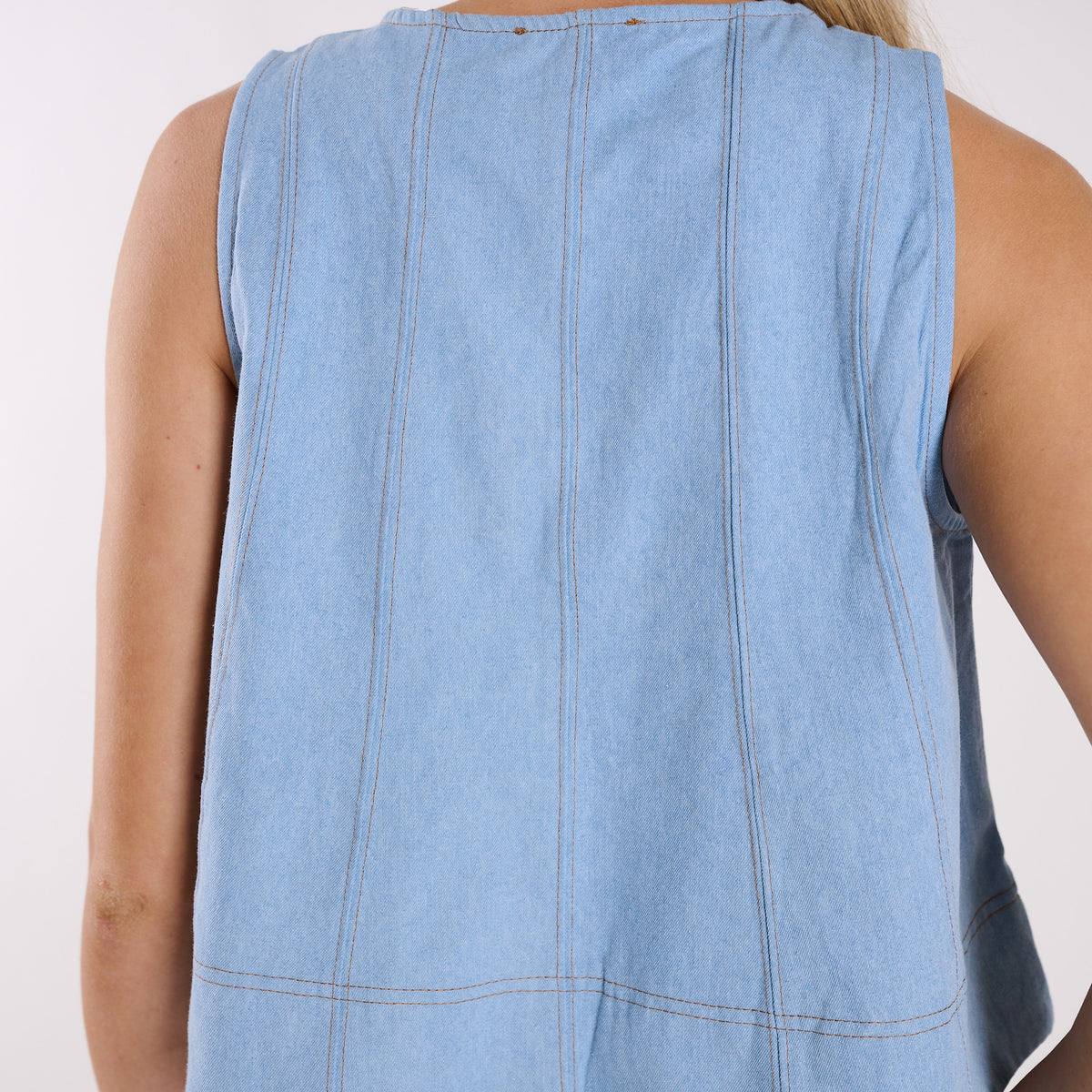 Light blue denim sleeveless top on a person against a white background