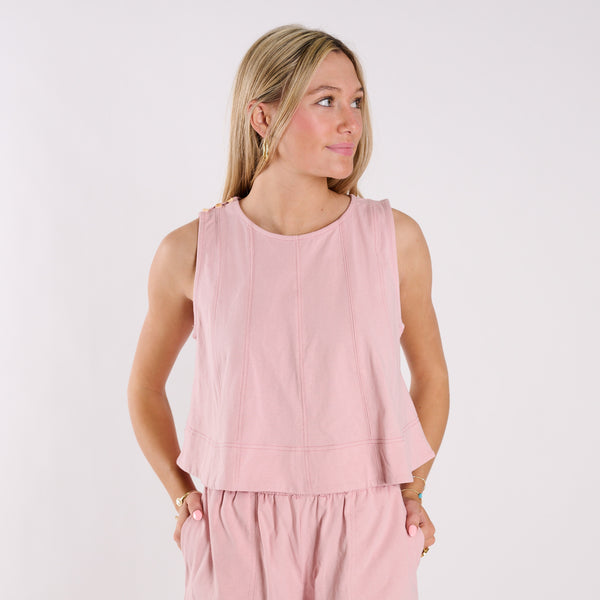  Woman wearing a pink sleeveless top and pants on a light gray background