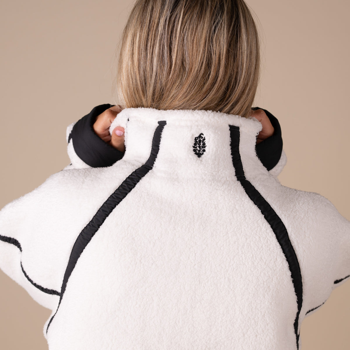 Woman wearing a white and black fleece jacket on a beige background
