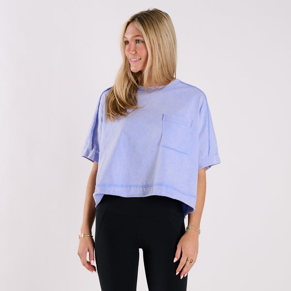  Woman wearing a light blue oversized cropped shirt and black pants on a white background