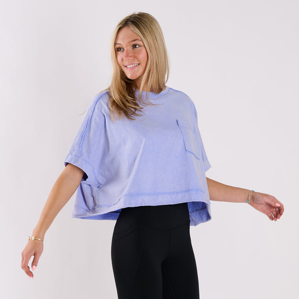  Woman wearing a light blue oversized cropped shirt and black pants on a white background