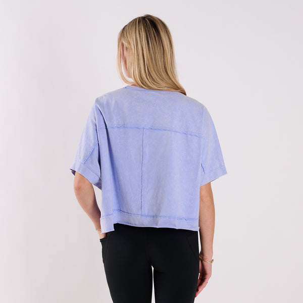  Woman wearing a light blue oversized cropped shirt and black pants on a white background