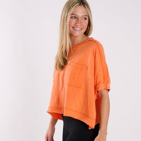  Woman wearing an orange oversized cropped shirt and black pants on a white background