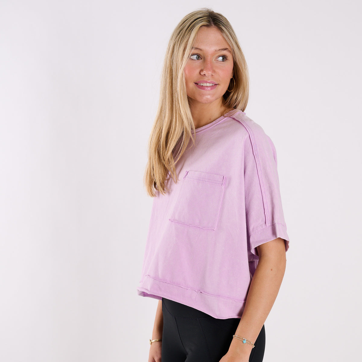 Woman wearing a lavender oversized cropped shirt and black pants on a white background