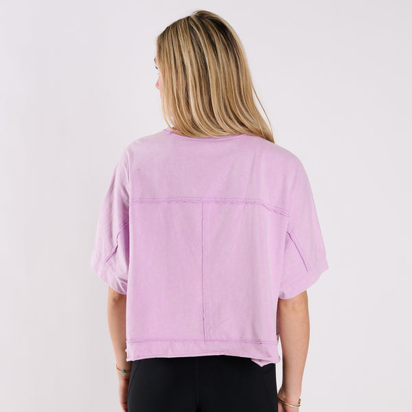  Woman wearing a lavender oversized cropped shirt and black pants on a white background