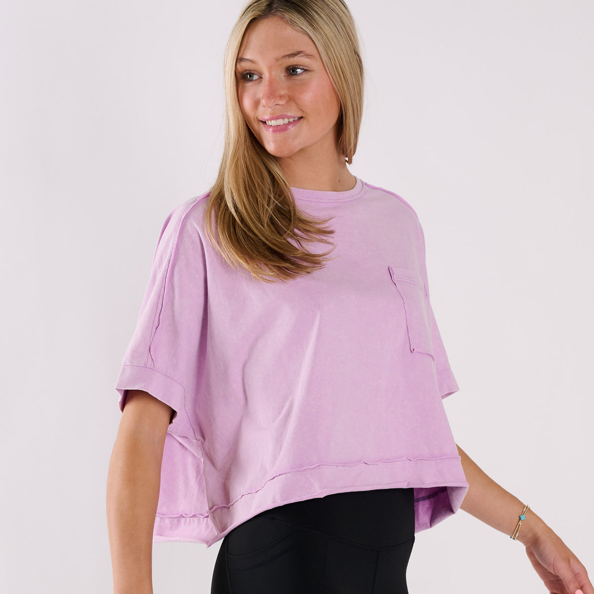 Woman wearing a lavender oversized cropped shirt and black pants on a white background