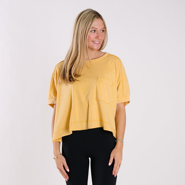  Woman wearing a yellow oversized cropped shirt and black pants on a white background
