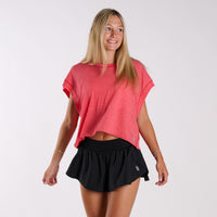Woman wearing a reddish pink FP Movement top and black shorts.