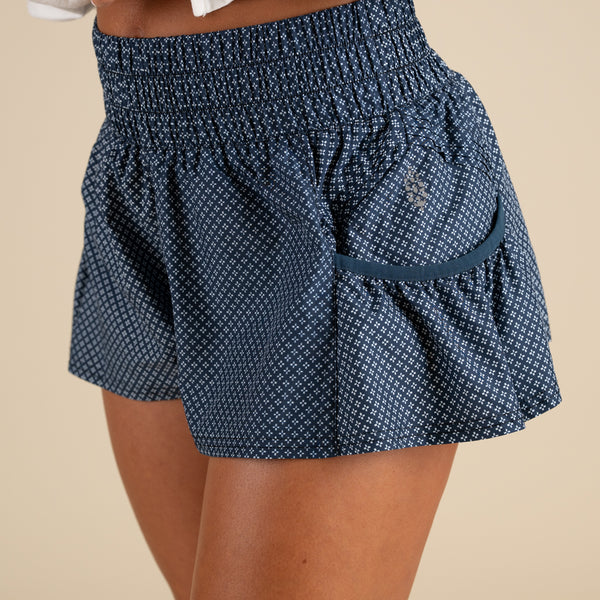 Blue patterned shorts worn by a person on a beige background