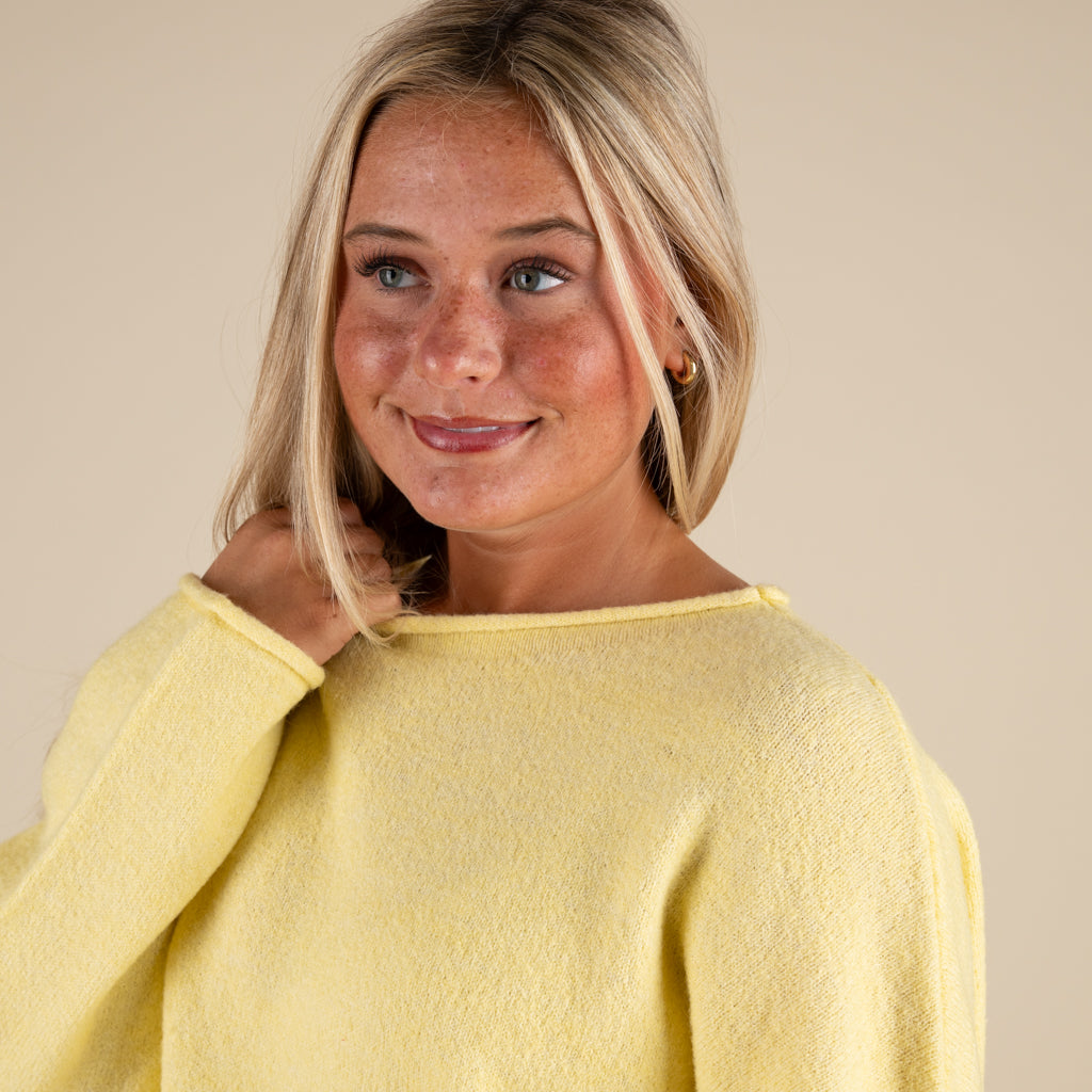 Woman wearing a yellow sweater against a beige background