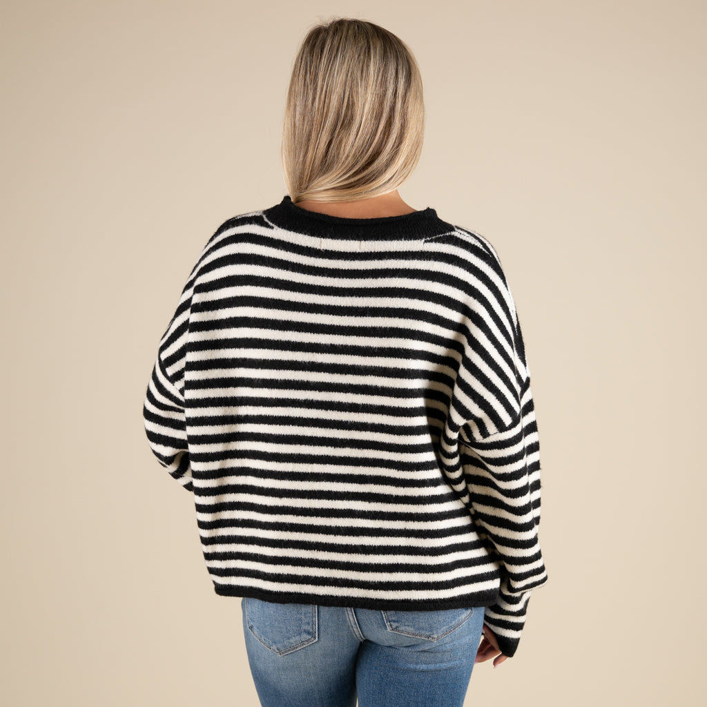 Person wearing a black and white striped sweater on a beige background