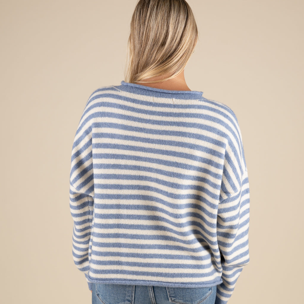 Person wearing a blue and white striped sweater on a beige background