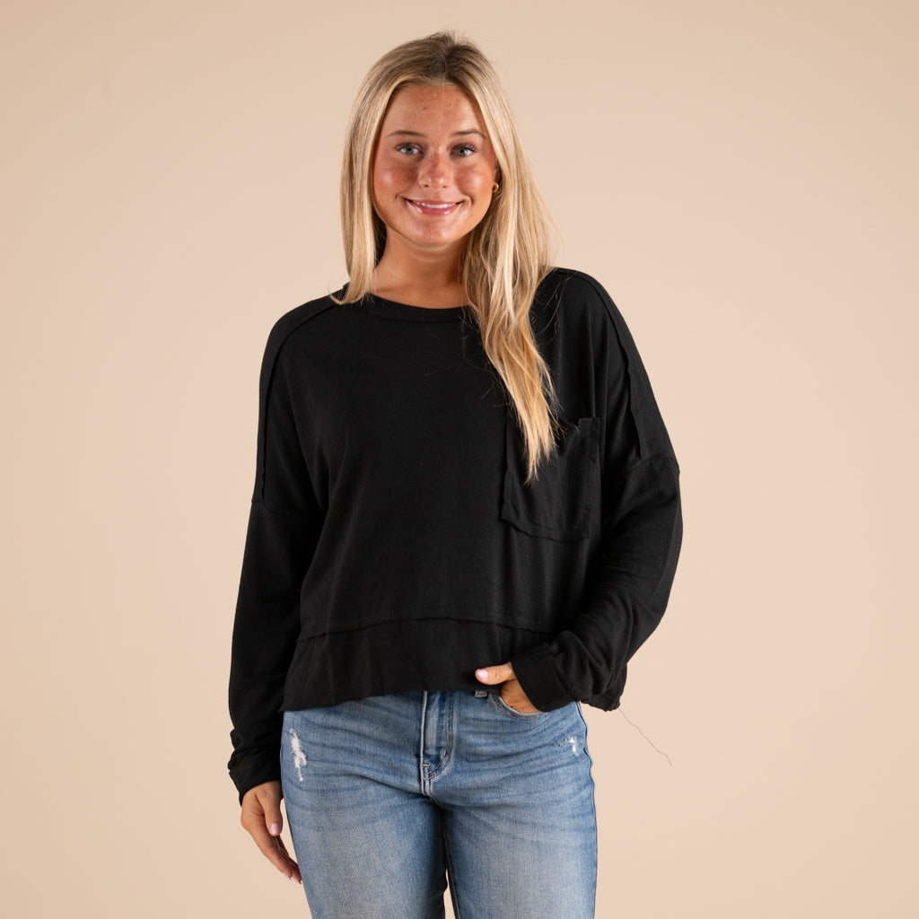 Woman wearing a black top and blue jeans against a beige background