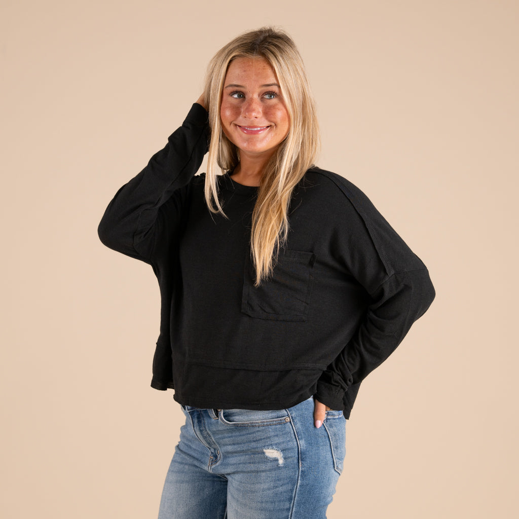 Woman wearing a black top and blue jeans against a beige background