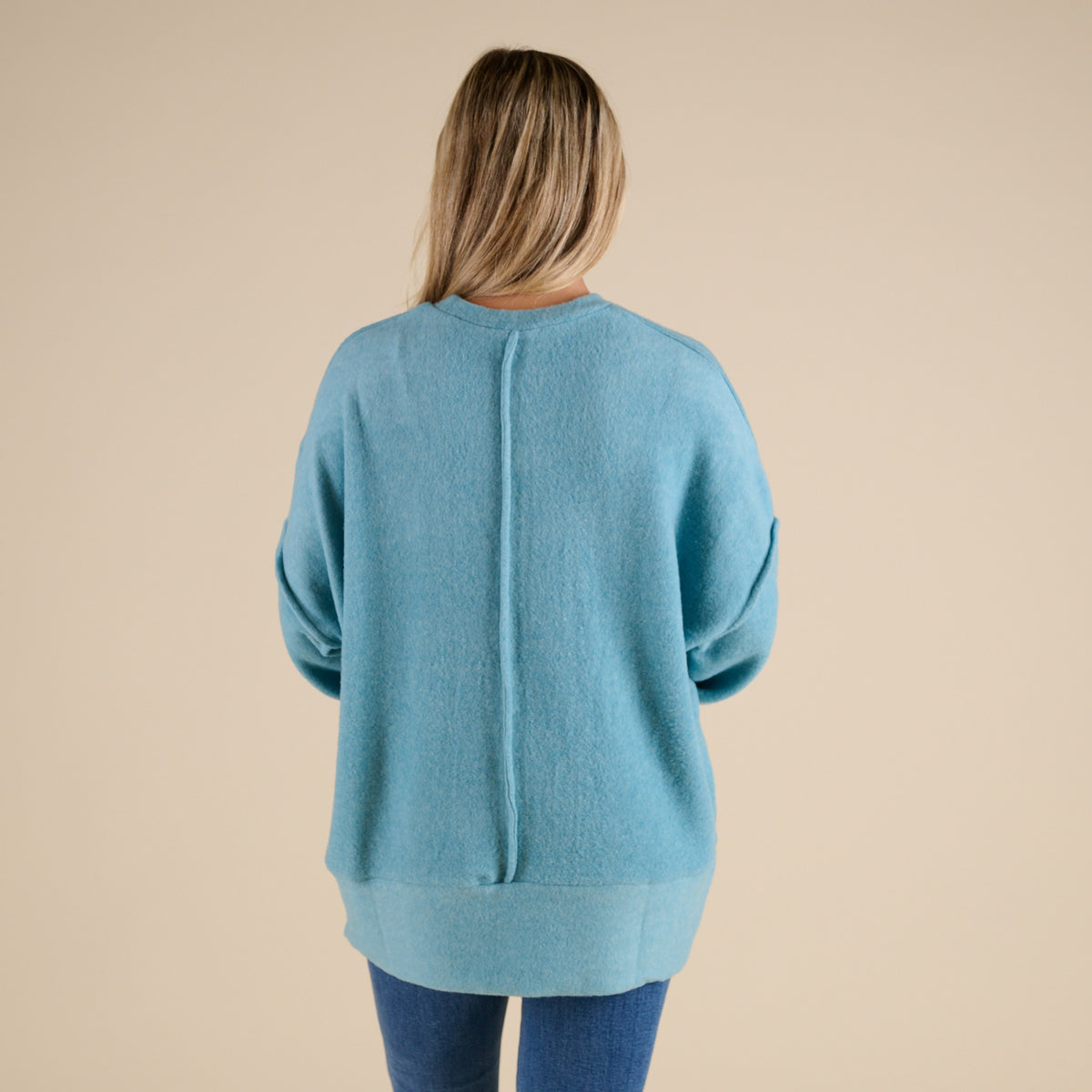 Person wearing a blue sweater on a beige background