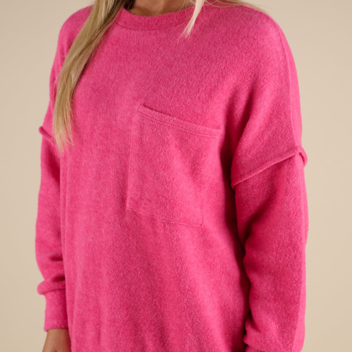 Pink sweatshirt worn by a person on a beige background