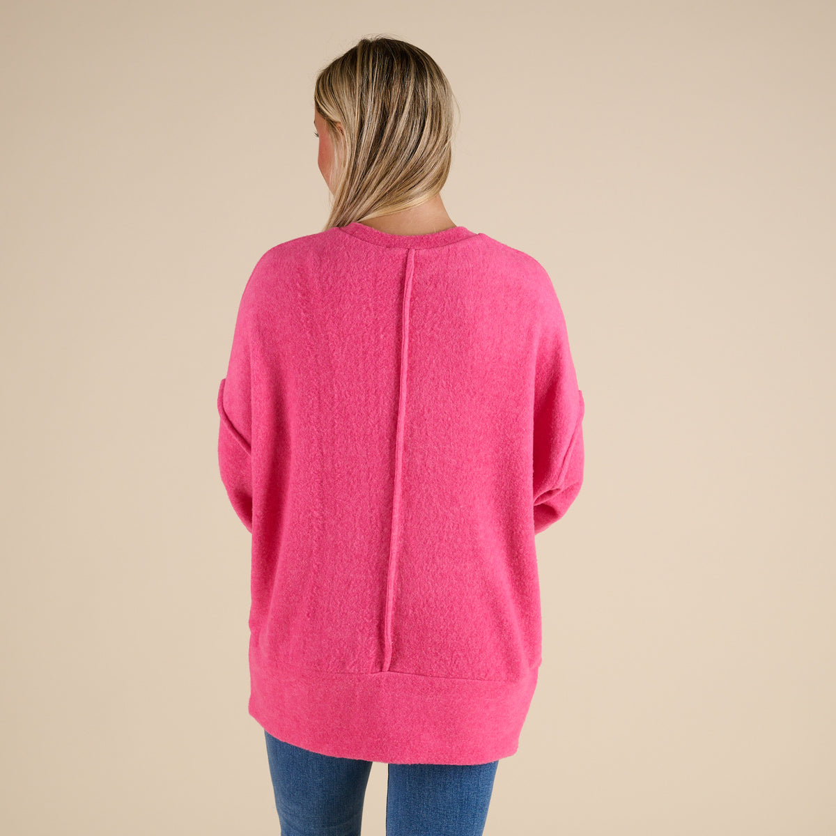 Person wearing a pink sweater on a beige background