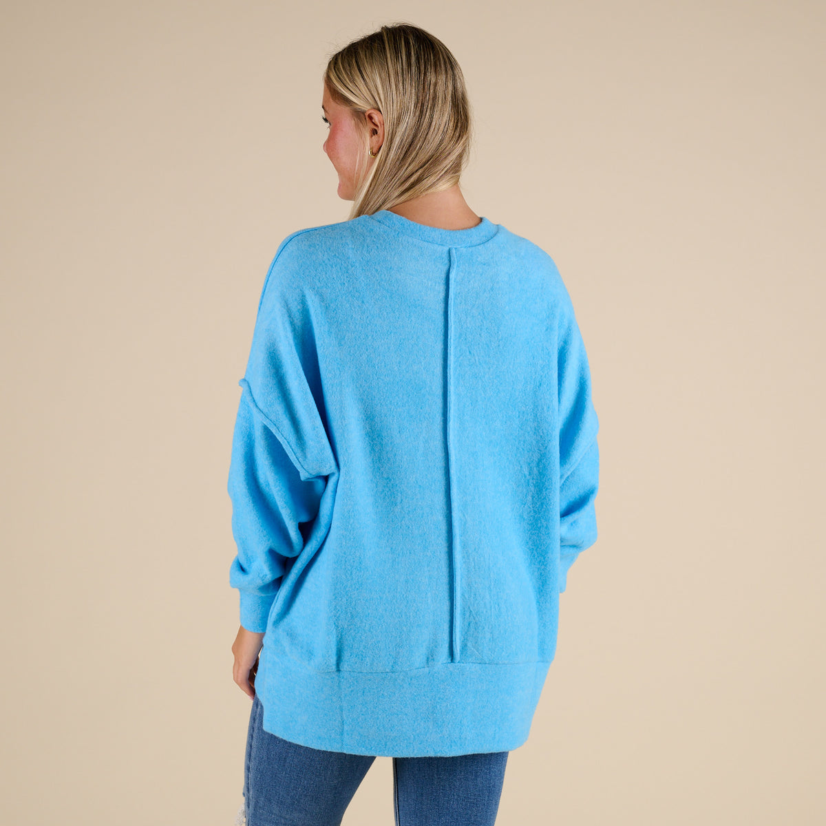 Person wearing a blue sweater on a beige background
