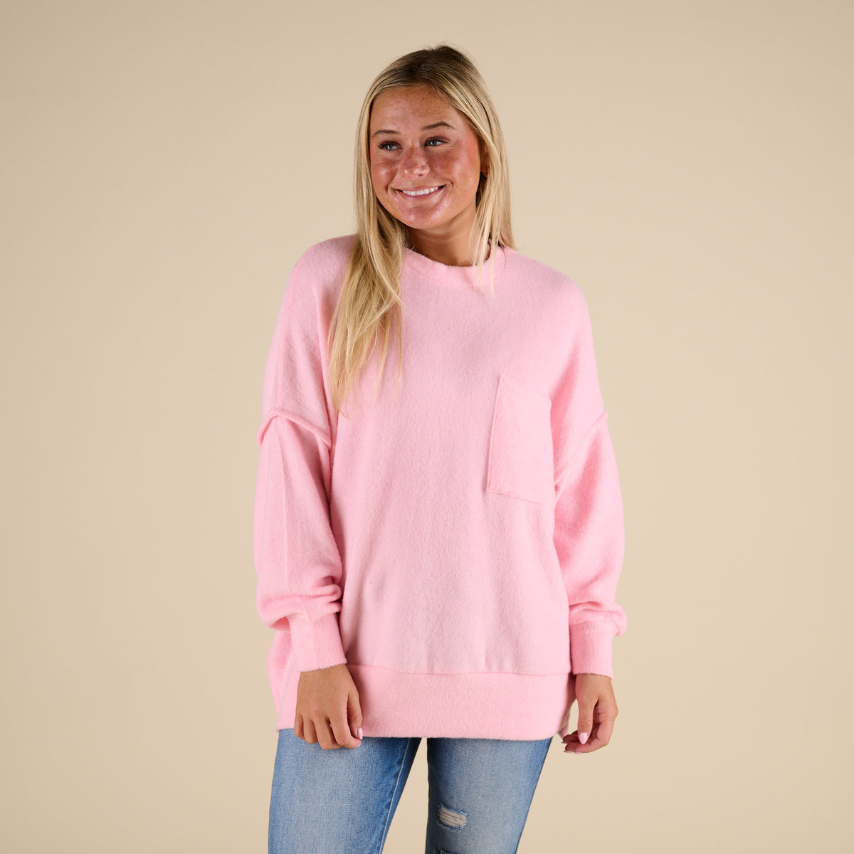 Woman wearing a pink sweater against a beige background