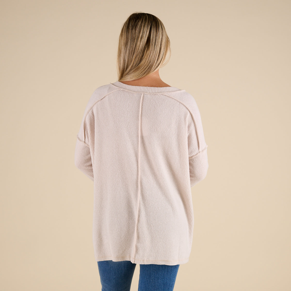 Person wearing a beige sweater with a plain background