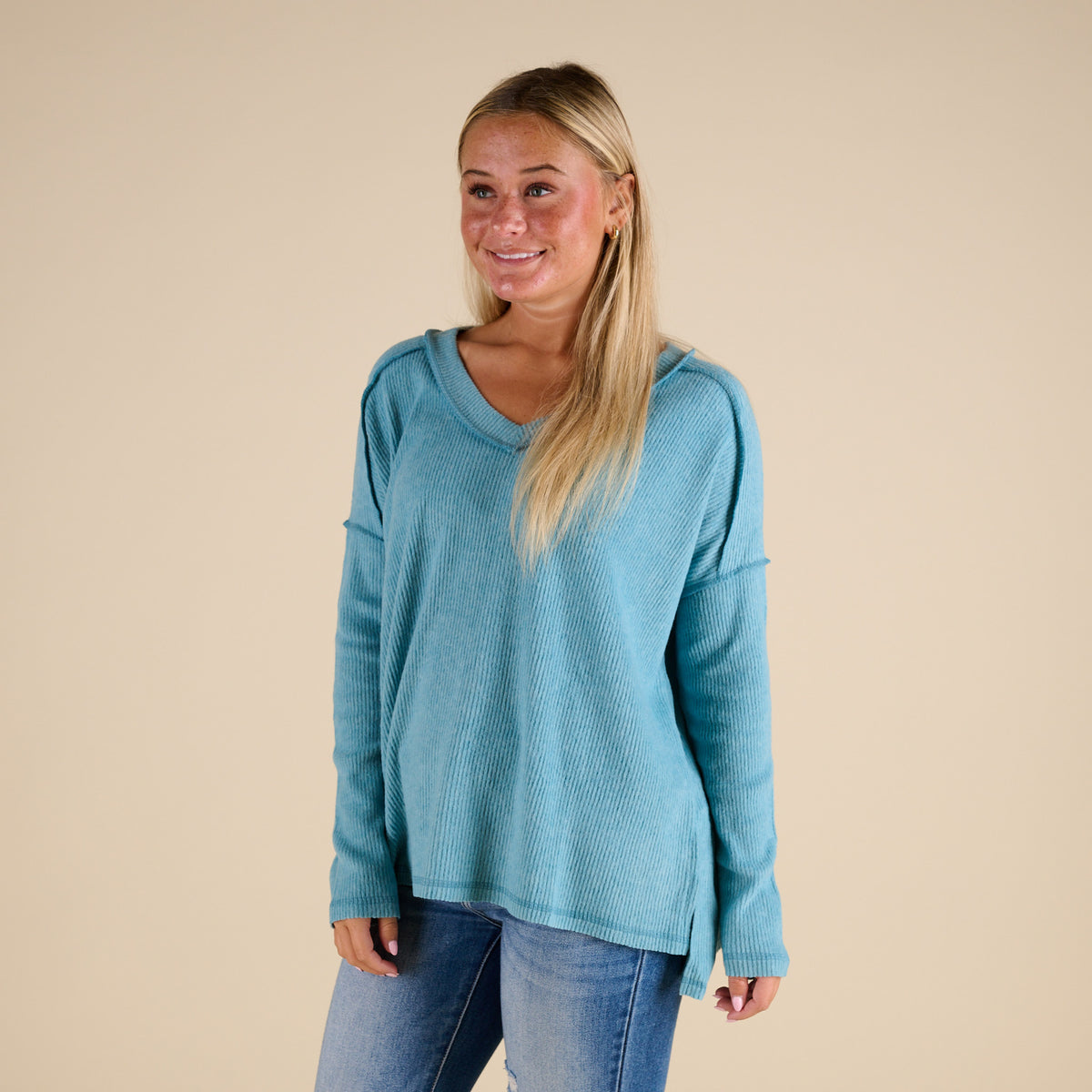 Woman wearing a blue sweater and jeans against a beige background