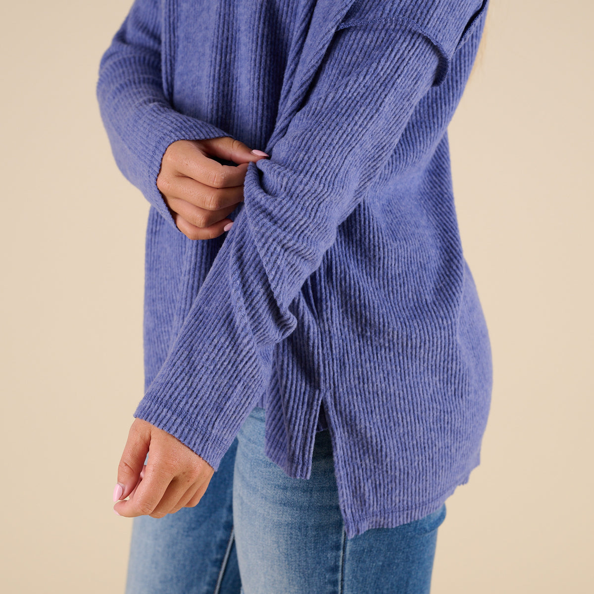 Person wearing a blue knitted sweater on a beige background