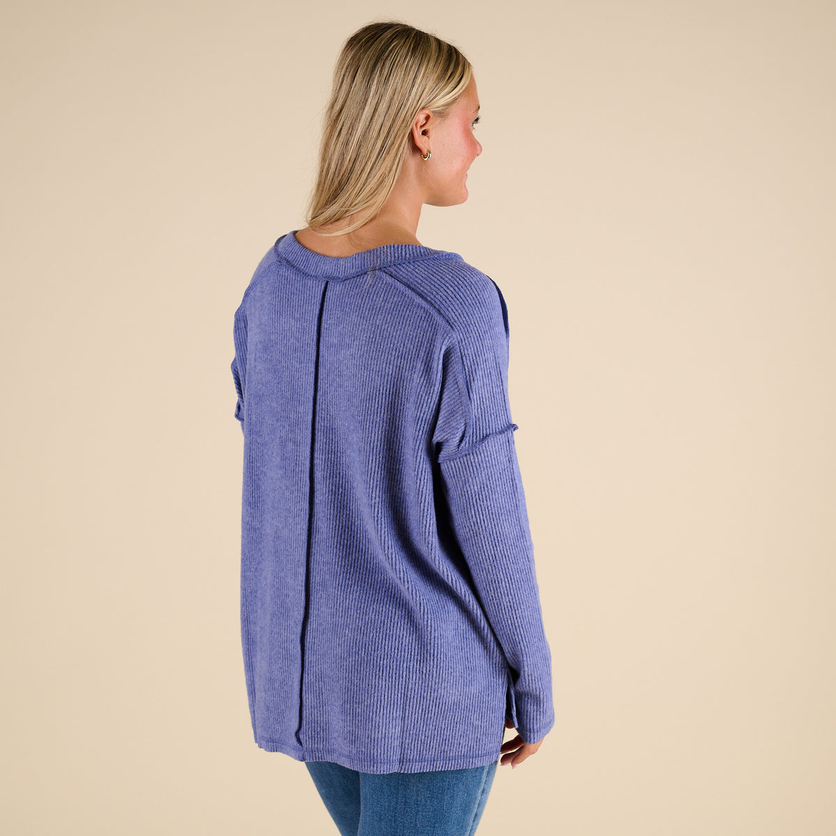 Woman wearing a blue sweater against a beige background