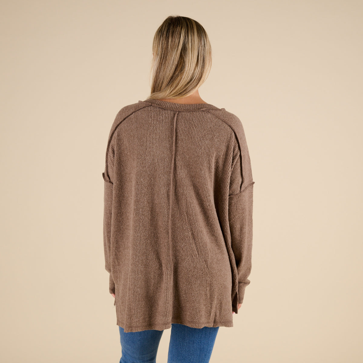 Person wearing a brown cardigan on a beige background