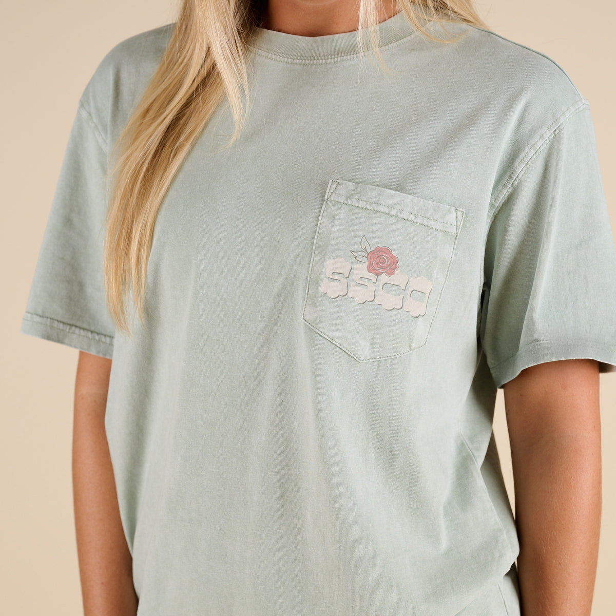 Light green t-shirt with a pocket design on a beige background