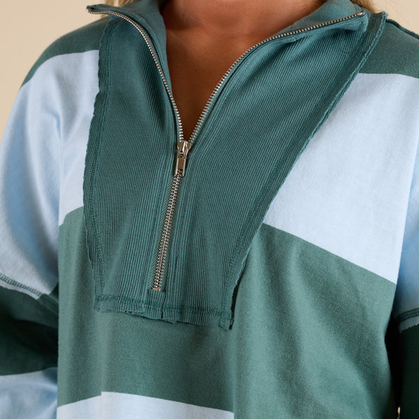 Model wearing FP Movement Retro Rugby Set in Heritage Green Combo, featuring an oversized half-zip striped top with pockets and matching striped shorts.