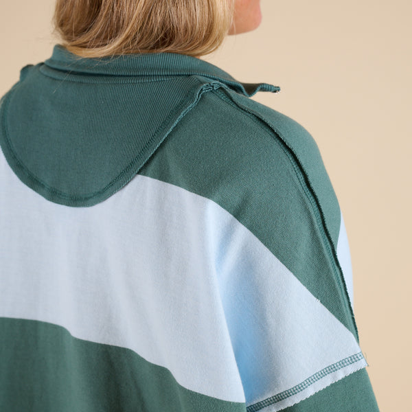 Model wearing FP Movement Retro Rugby Set in Heritage Green Combo, featuring an oversized half-zip striped top with pockets and matching striped shorts.