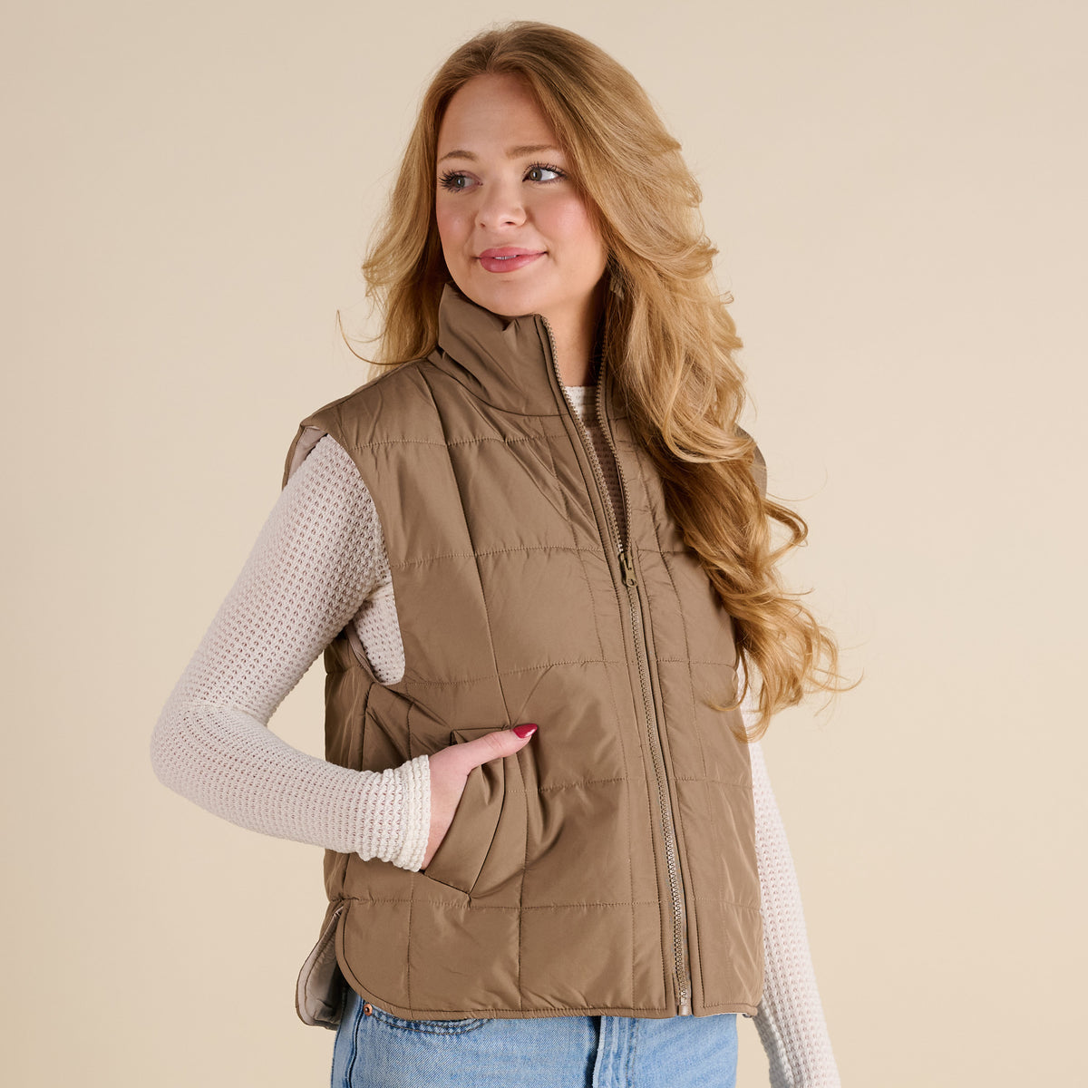 Woman wearing a brown quilted vest on a beige background