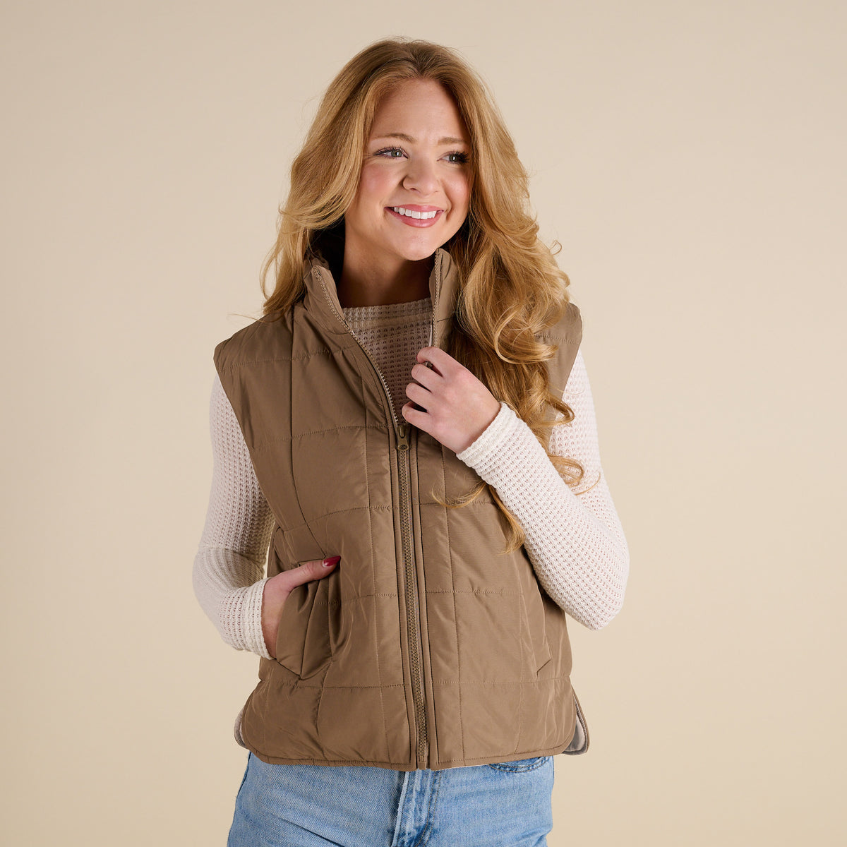 Woman wearing a brown vest over a white shirt on a beige background