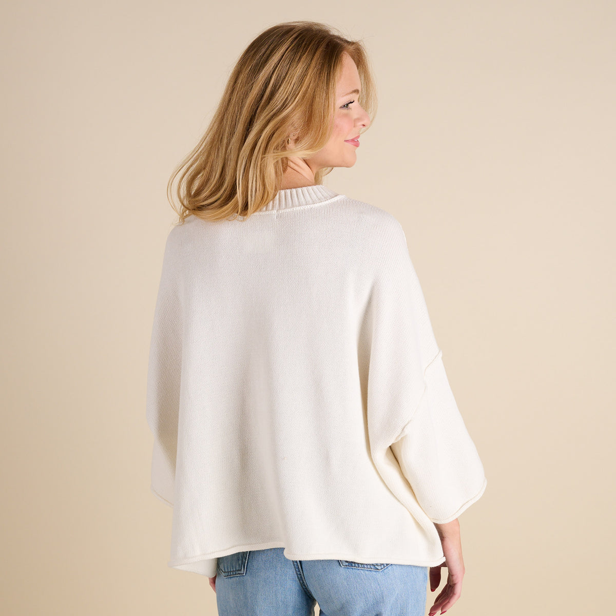 Women’s ivory knit mockneck sweater with relaxed fit, drop shoulders, and three-quarter sleeves, shown from the back with a straight hem and soft textured fabric.