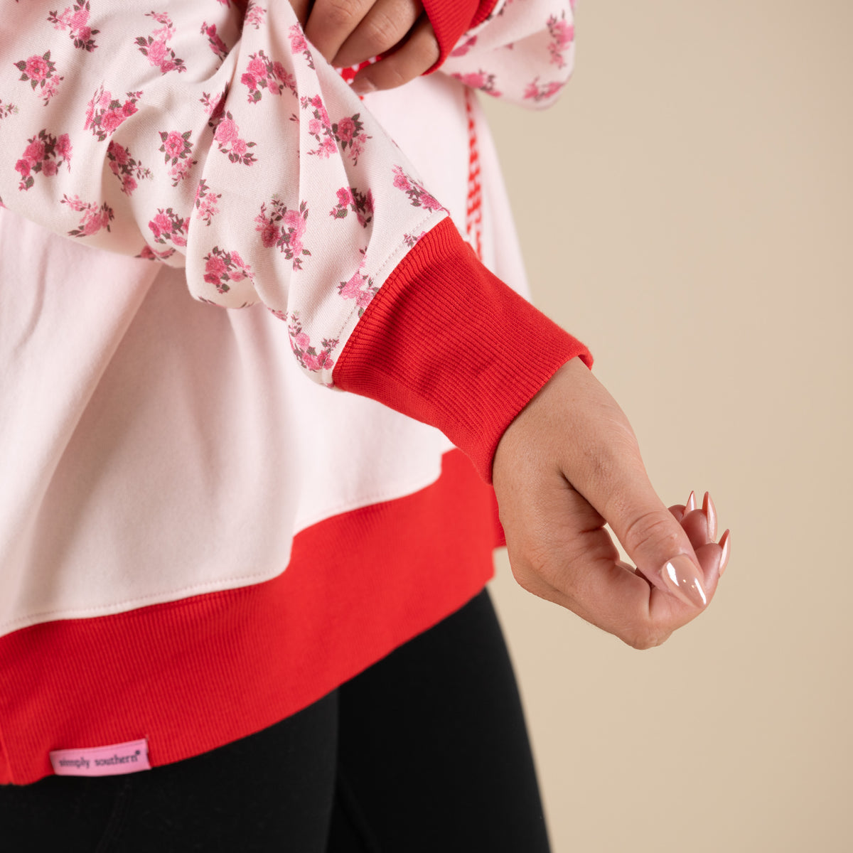 Simply Southern Bow Love Hoodie in Light Pink with contrasting red hood and hem, and floral sleeves.