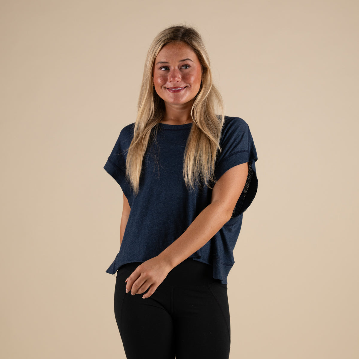 Woman wearing a navy blue activewear top with a cutout back and black leggings.