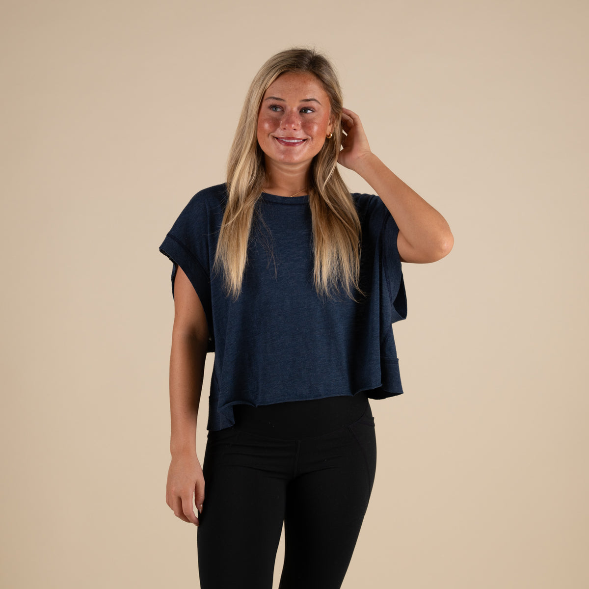 Woman wearing a navy blue activewear top with a cutout back and black leggings.