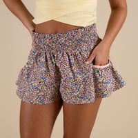 Woman wearing micro floral printed FP Movement shorts and holding her hand in her pocket.