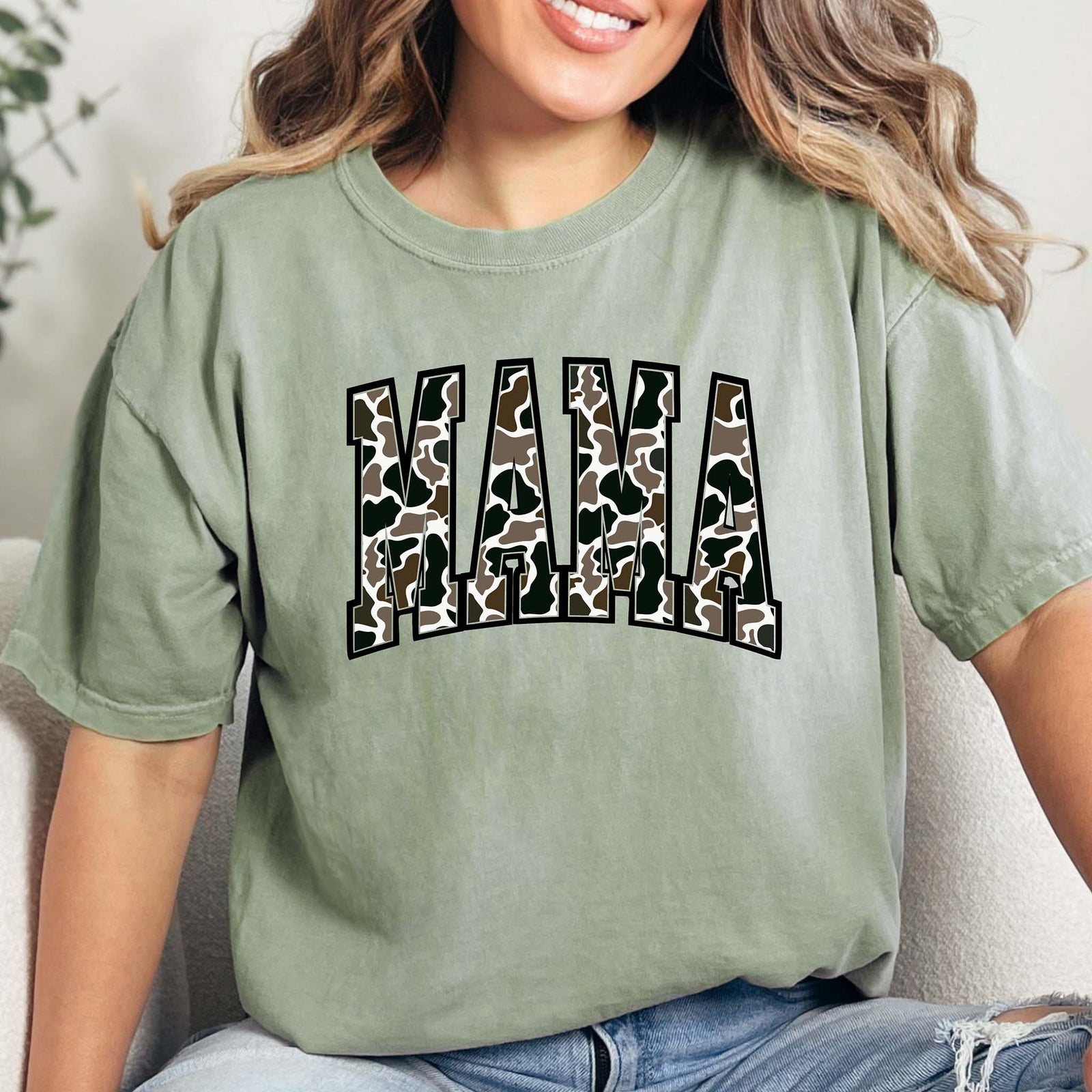 Duck Camo Mama Graphic T-Shirt – A soft cotton short-sleeve tee featuring the word 'Mama' in bold lettering filled with a classic duck camo pattern. Relaxed fit with a crew neckline, perfect for casual wear.