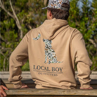 A man standing with his back turned to the camera wearing a local boy sweatshirt.