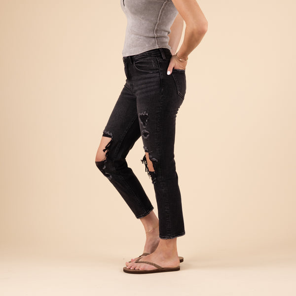 Side view of the black straight-leg jeans showing the relaxed fit through the leg and visible knee distressing on one side. The jeans maintain a clean line from hip to ankle.