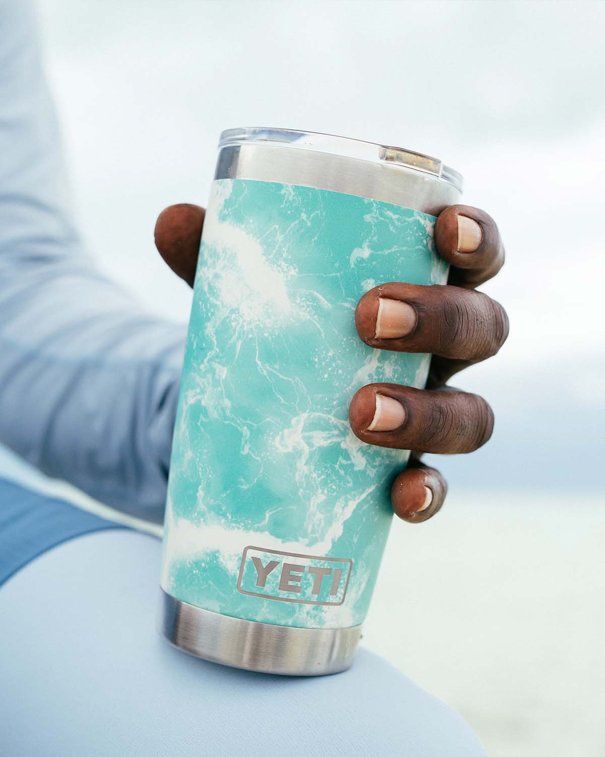 A man holding a YETI seafoam 20oz tumbler.