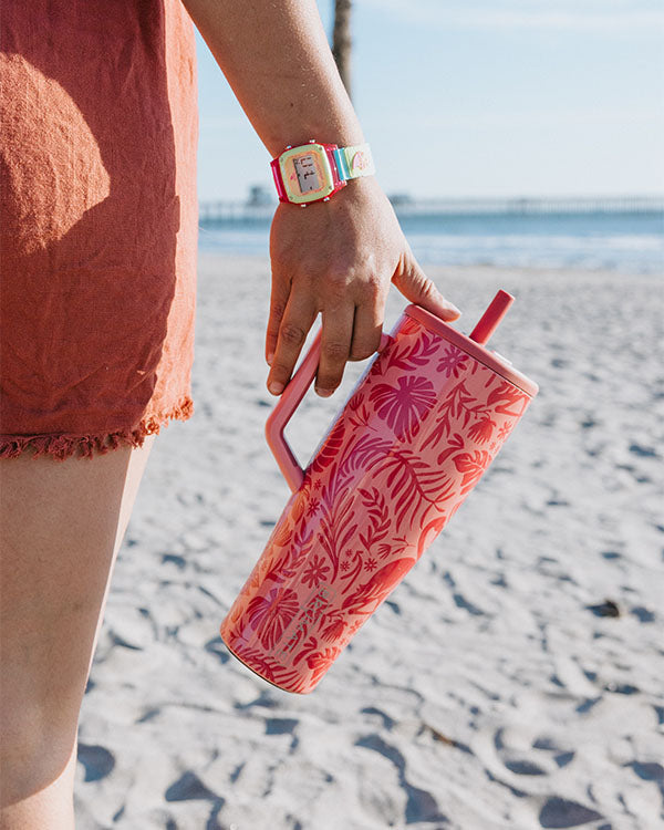 girl holding a brumate era tumbler on the beach