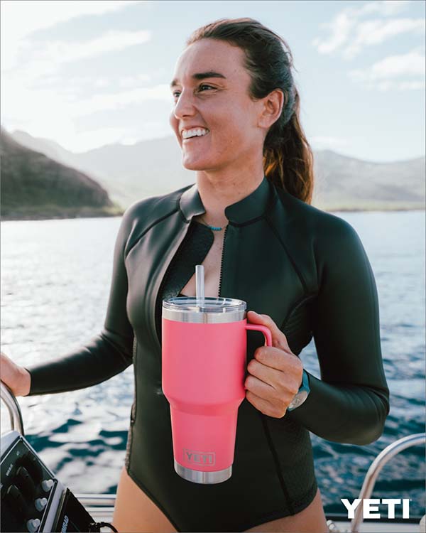 girl standing on a boat posing for a picture with a YETI tropical pink tumbler